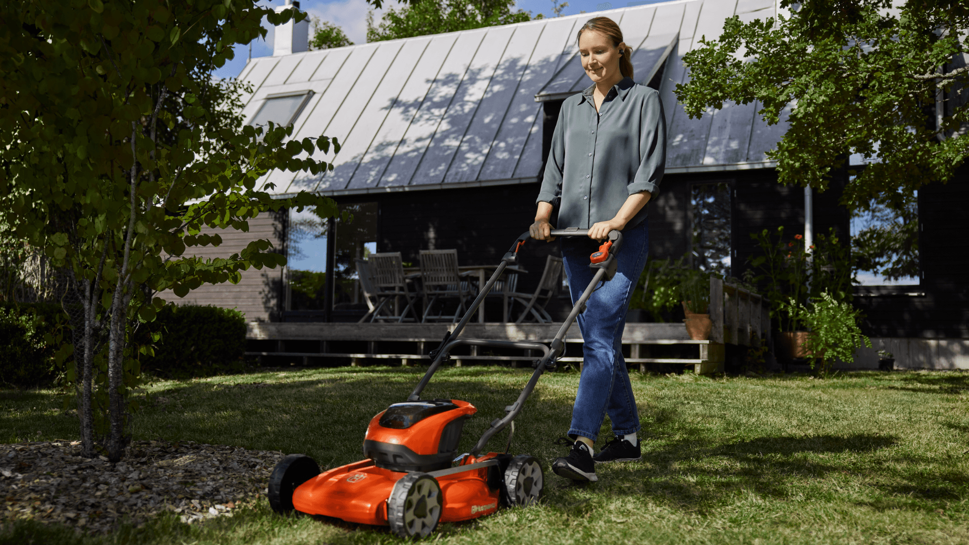 woman pushing lawn mower in backyard